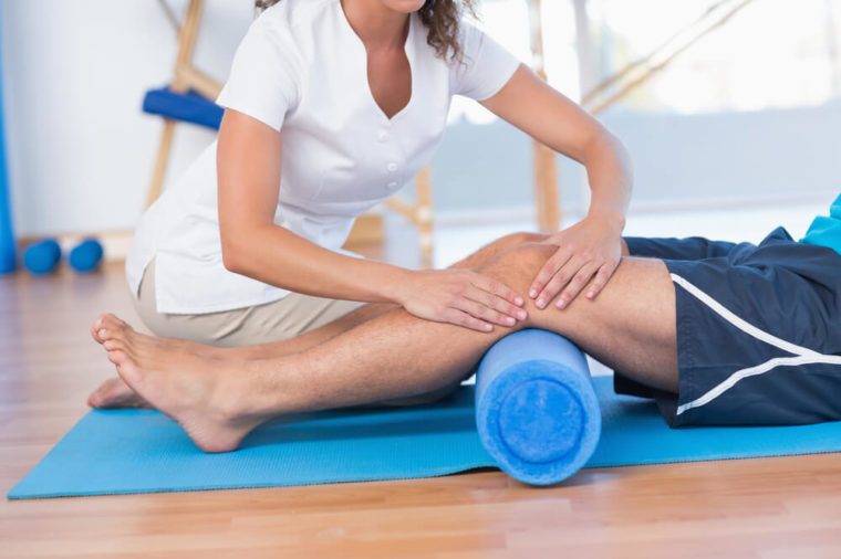 Trainer working with man on exercise mat in fitness studio