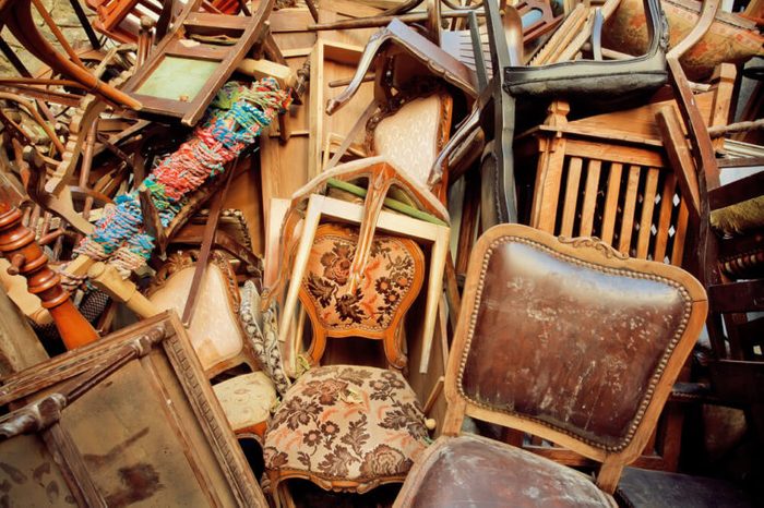 Vintage wooden furniture in trash warehouse of antique market. Retro background