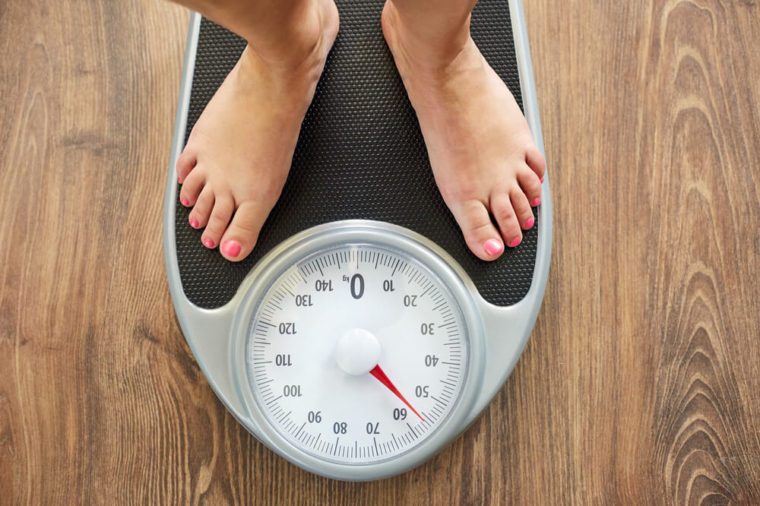 Female bare feet on weight scale, top view
