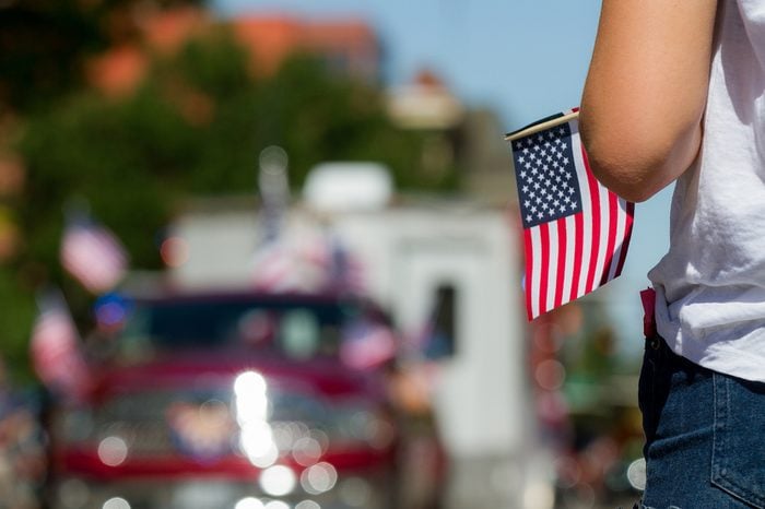 Girl holding an american flag with a parade float in the background