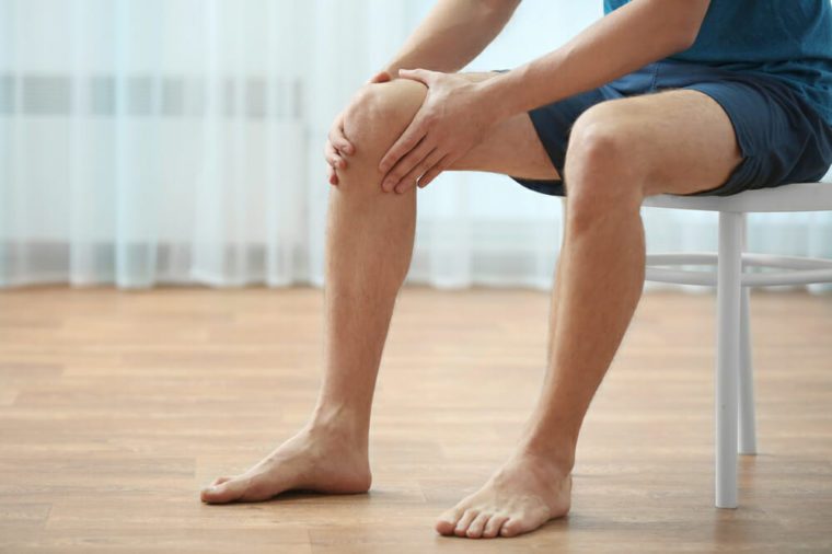 Young man suffering from knee pain at home