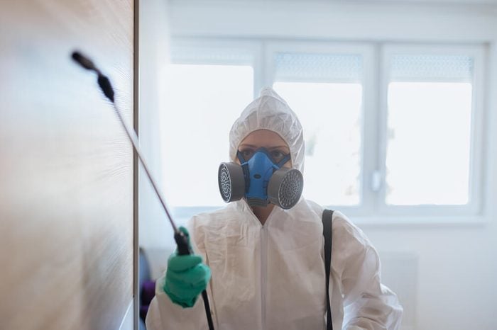 Exterminator in workwear spraying pesticide with sprayer.