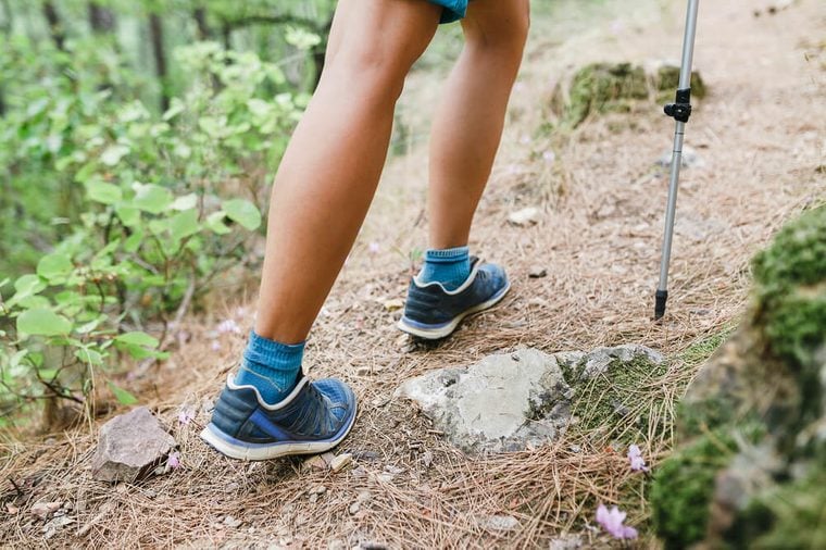 Closeup of young fitness woman legs walking on forest hiking trail