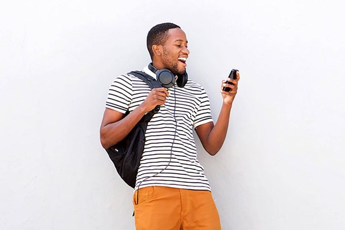 Portrait of happy young african man with skateboard looking at mobile phone