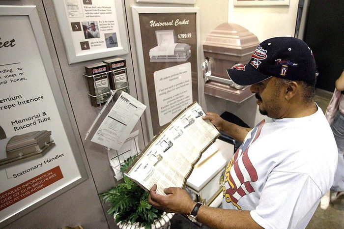 Tomas Torres Reads a Brochure Which Shows the Prices and the Size Options of Coffins in Front of the Casket Display Inside a Costco Warehouse Store in Chicago August 24 2004 the World's Largest Warehouse Club Operator Said on Tuesday It Began a Test Program That Offers Coffins at Two of Its Chicago Area Stores the Issaquah Washington-based Company Said the Two Stores Are Now Offering Six Different Models of Steel Coffins That Are Made by Universal Casket Co Based in Michigan the Retailer Has Set Up a Special Order Program in Which Customers Can Select a Coffins in Either of the Two Locations and Have It Shipped to Their Mortuary of C United States Chicago