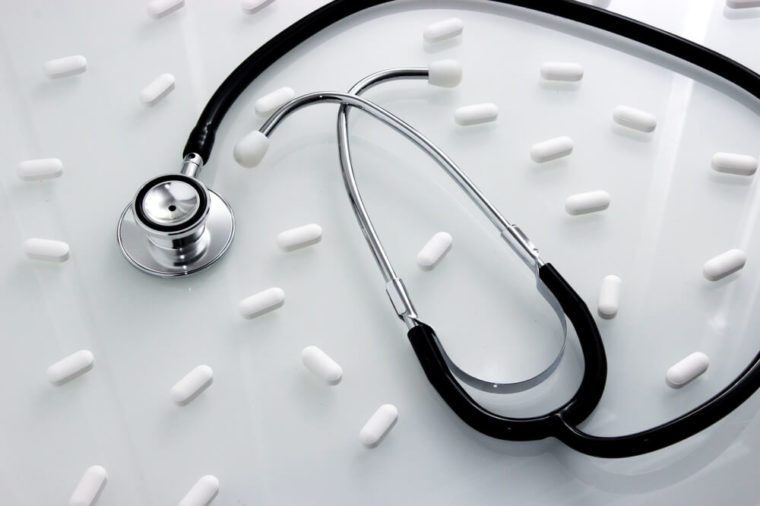 Stethoscope surrounded by white prescription medication pills