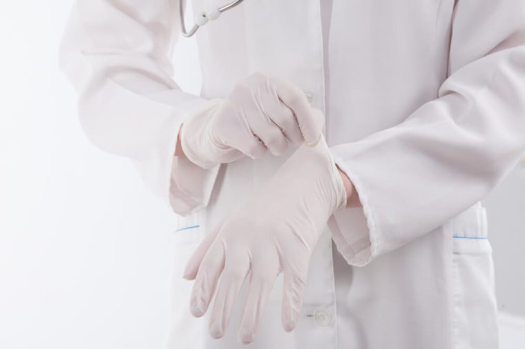 Doctor putting on protective gloves, isolated on white