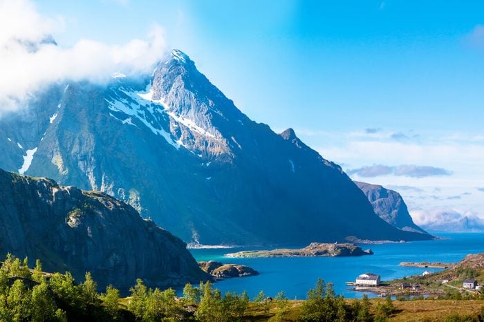 Scenic fjord on Lofoten islands with typical fishing hut and towering mountain peaks