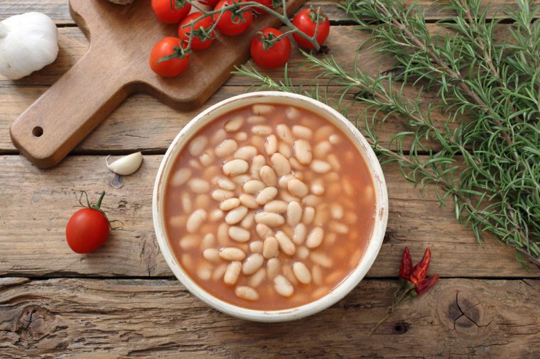 White beans in tomato sauce in a bowl on rustic table background
