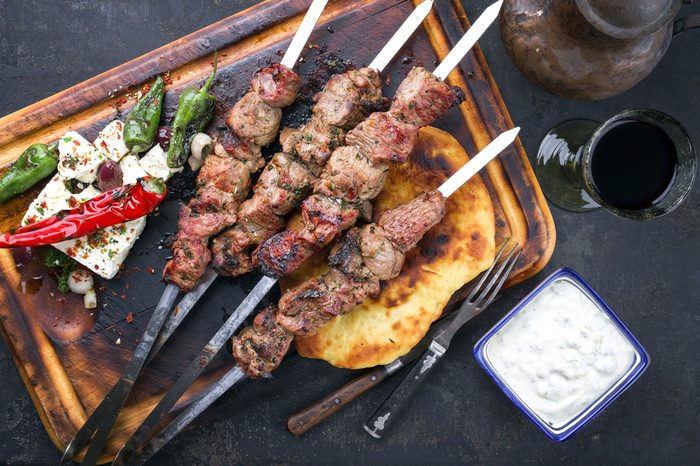 Traditional Greek Souvlaki with Feta and Pita Bread as top view on an old burnt cutting board 