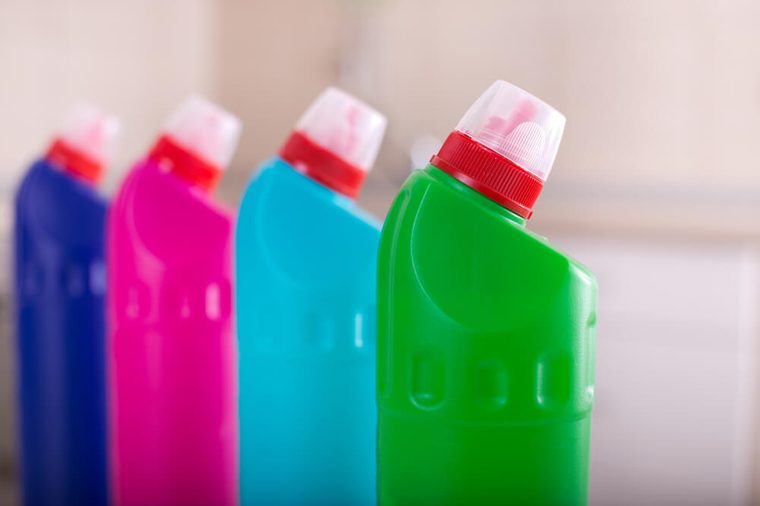 Close up of group of colorful cleaning supplies with tiled wall in background. House keeping and hygiene concept
