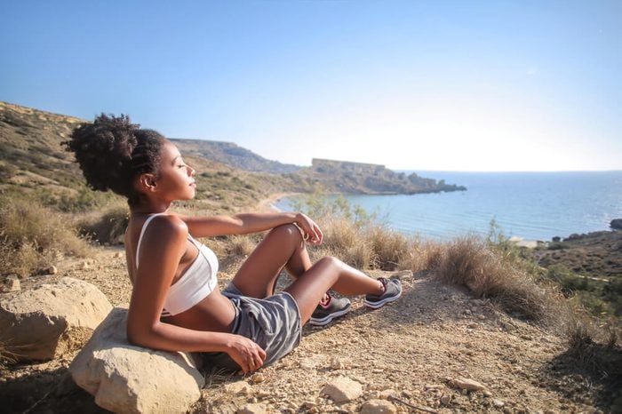 Girl relaxing on a cliff, looking the sea