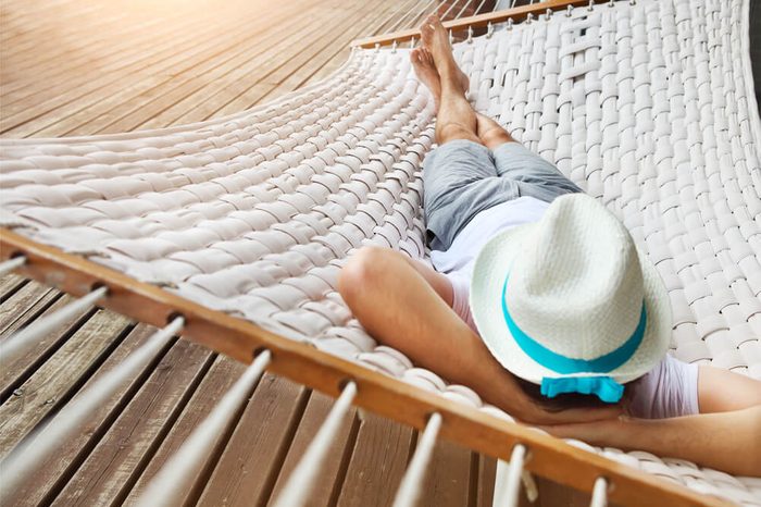 Lazy time. Man in hat in a hammock on a summer day