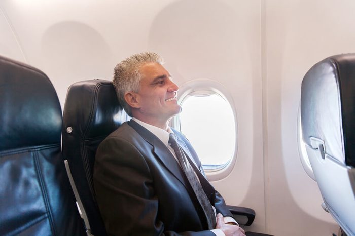 happy middle aged airplane passenger relaxing during flight on air plane 
