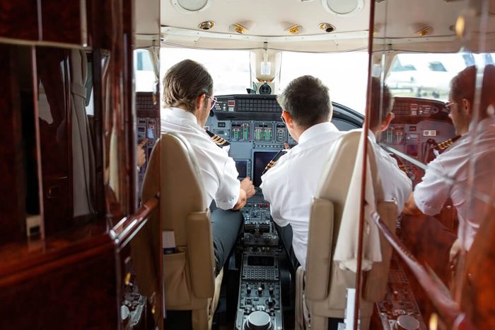 Rear view of pilot and copilot operating controls of private jet
