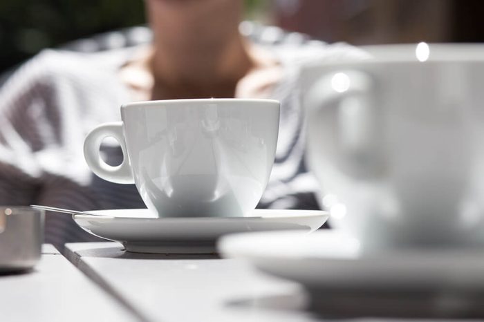detail shot of white coffee cups on a grey wooden table outdoors