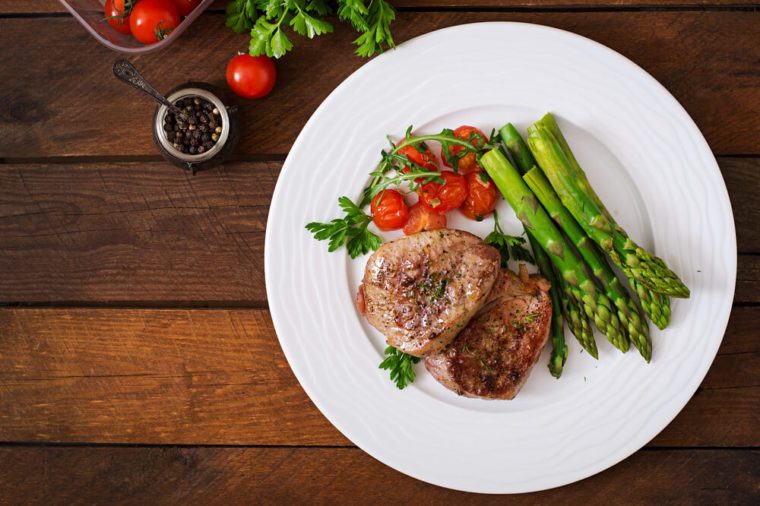 Barbecue grilled beef steak meat with asparagus and tomatoes. Top view