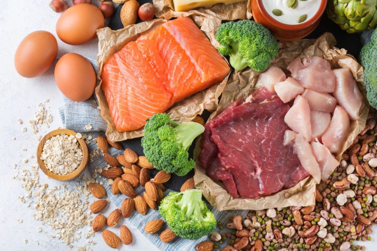 Assortment of healthy protein source and body building food. Meat beef salmon chicken breast eggs dairy products cheese yogurt beans artichokes broccoli nuts oat meal. Top view