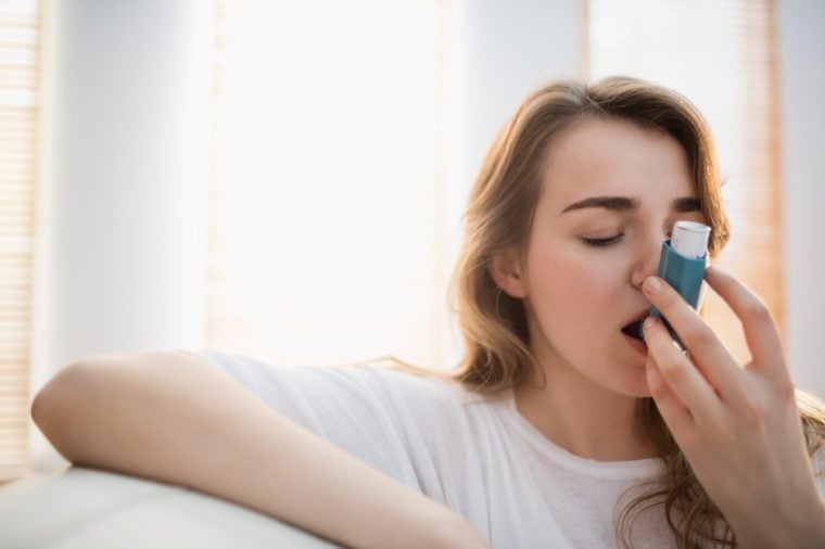 Woman using her inhaler on couch in the living room