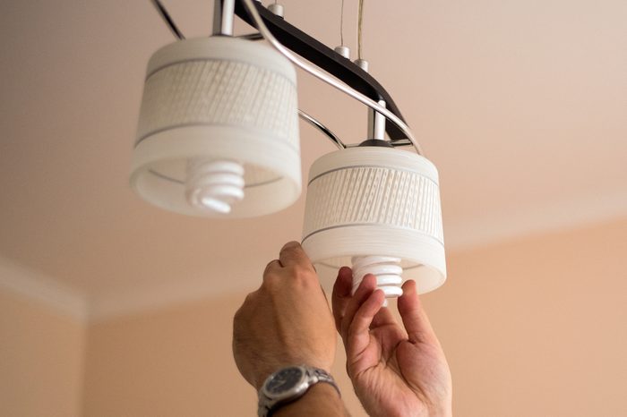 Man changes an electric light bulb, energy efficiency. Closeup of man's hand adjusting electric bulb by pendant lights at home.energy efficiency,. LED lamp