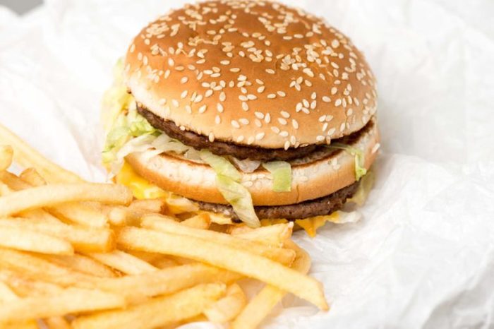 Double burger with french fries on white paper