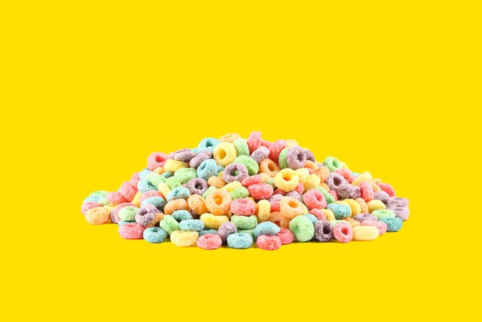 pile of fruit loops cereal on yellow background