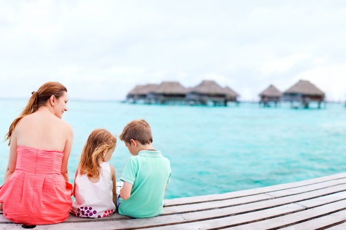 Mother and kids sitting at wooden dock enjoying ocean view
