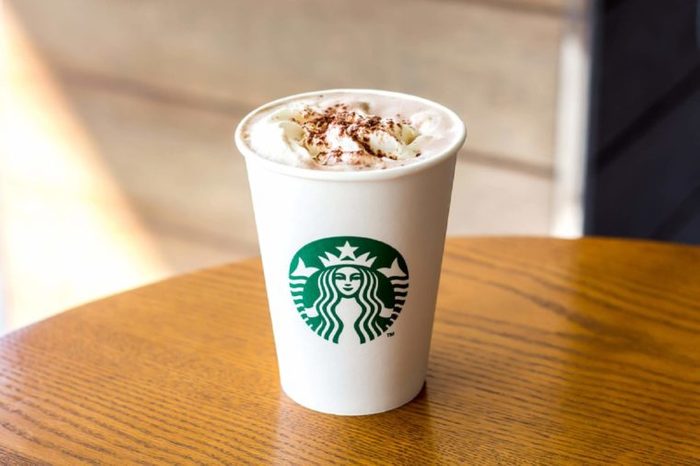 Bangkok, Thailand - December 21, 2017 : Starbucks Hot chocolate with whipping cream in white paper cup on wooden table background with copy space.
