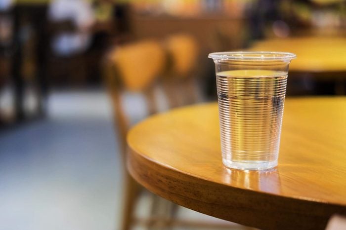 Plastic cup of water on round wooden table
