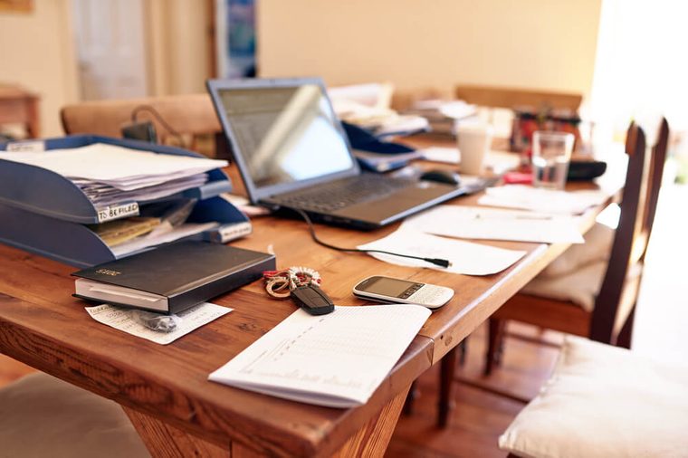 Still life images of a busy entrepreneur's desk in their home office space, with technology and paperwork cluttering the table space