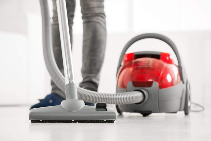 Woman vacuuming the house. Close-up with vacuum cleaner.
