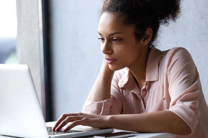 Close up portrait of a young black woman looking at laptop