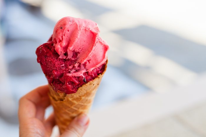 Close up of woman hand holding fresh waffle cone with raspberry sorbet