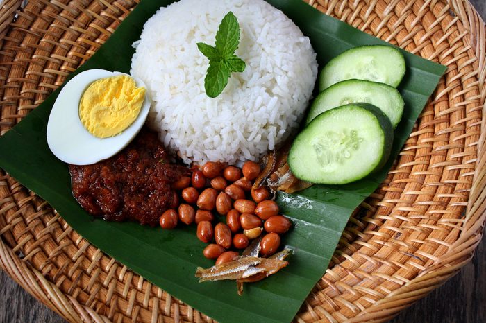 Nasi Lemak-Malaysian cuisine. A fragrant rice dish cooked in coconut milk and pandan leaf commonly found in Malaysia. Served with sambal, anchovies, peanut and cucumber.