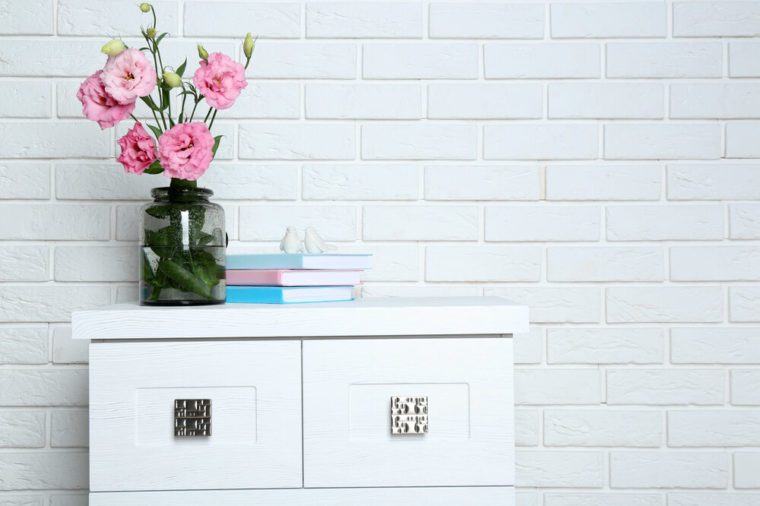 Beautiful flowers with books on brick wall background