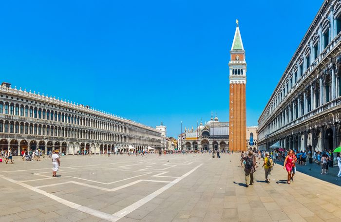 Beautiful panoramic view of historic Piazzetta San Marco with Doge's Palace and famous St Mark's Campanile, Procuratie and coffee places on a sunny day with blue sky, Venice, Italy