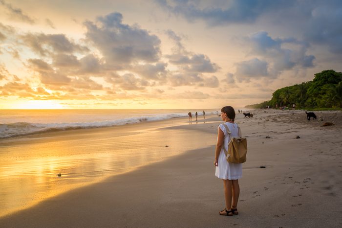 Costa Rica, young girl looking at the ocean at sunset, Playa Carmen.