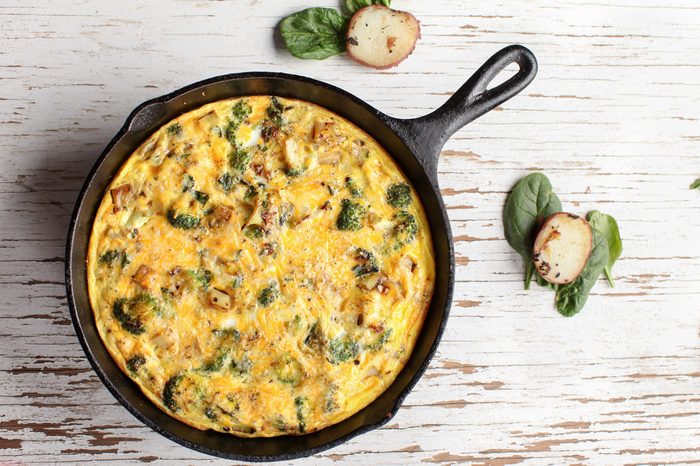 Baked egg frittata with spinach, cheese, broccoli, red potatoes, bacon, milk, and spinach far away shot from top