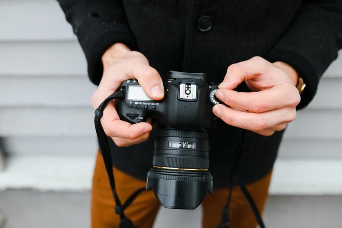 A professional photographer adjusts the camera before shooting, hands, camera, background