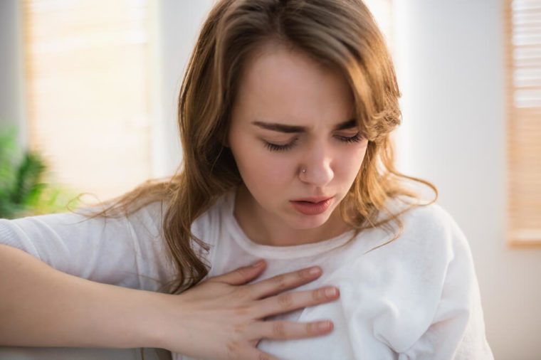 Pretty woman suffering from chest pain on couch
