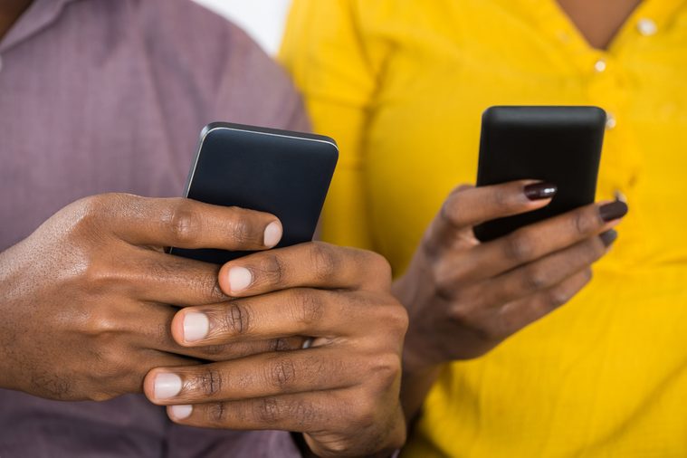 Close-up Of African Couple Holding Mobile Phones In Hand