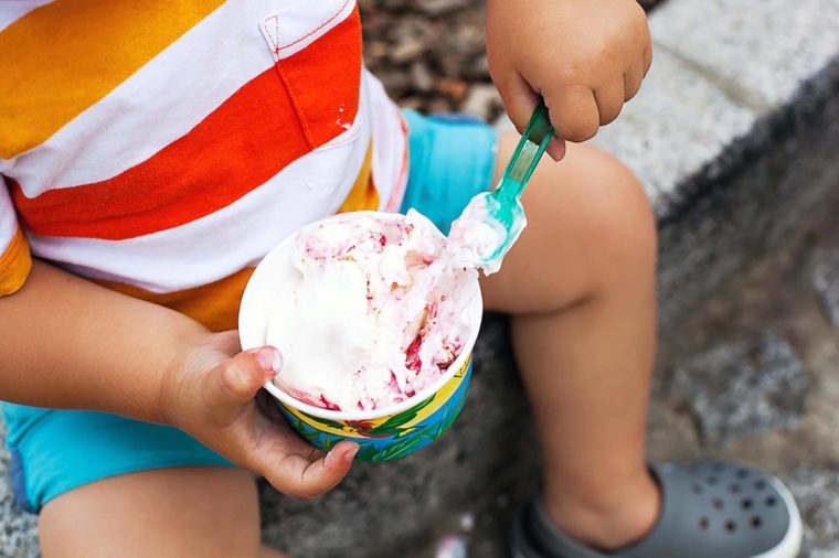 Close-up detail of child eating ice cream. Outdoor at the cafe