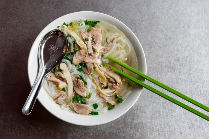 pho ga, vietnamese chicken rice noodle soup with chicken, herbs.on a table from scratched aluminum