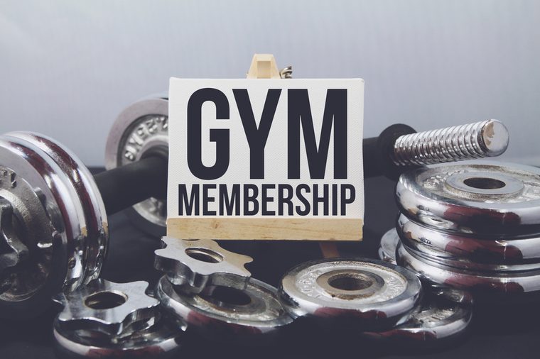 A Concept image of Fitness or bodybuilding background with a dumbbell and extra plates. Vintage tone and a wooden stand with a white frame and a word Gym Membership