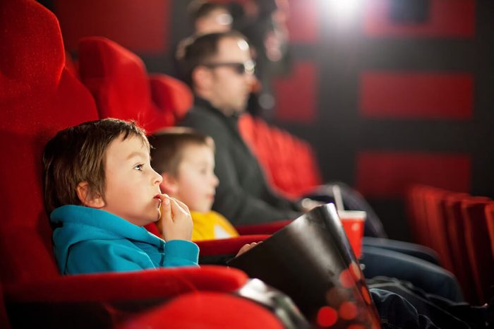 Father and two children, boys, watching cartoon movie in the cinema on 3D