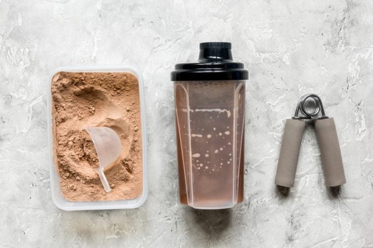 Fitness nutrition with shaker, bars on stone background top view