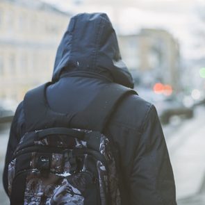 Student with backpack walking through foggy city street