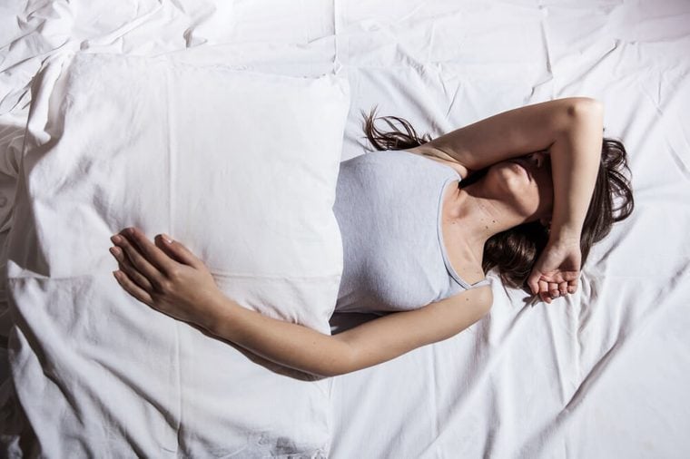 Young woman with insomnia cover her face with hand in bed