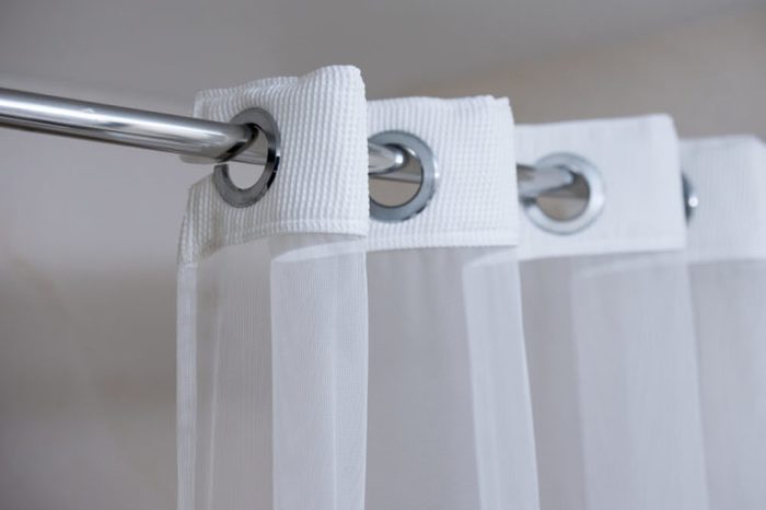 Shower curtain hanging from a chrome shower curtain rod