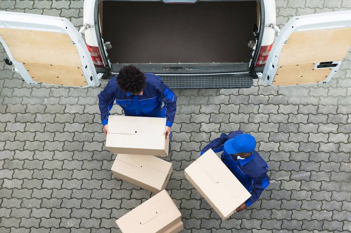 High Angle View Of Delivery Men Unloading The Cardboard Boxes From Truck